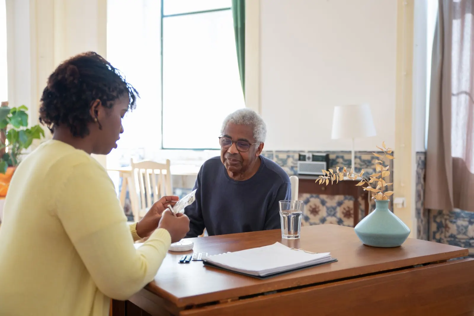 Zorgverlener in gesprek met een oudere man aan de keukentafel